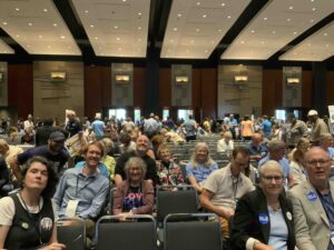 Cville Dems are seated and waiting for a large auditorium to fill with more delegates to the state convention in July 2024.