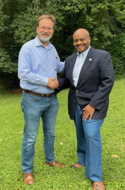 Outdoor photo of Bryan Pinkston and Juandiego Wade, shaking hands.