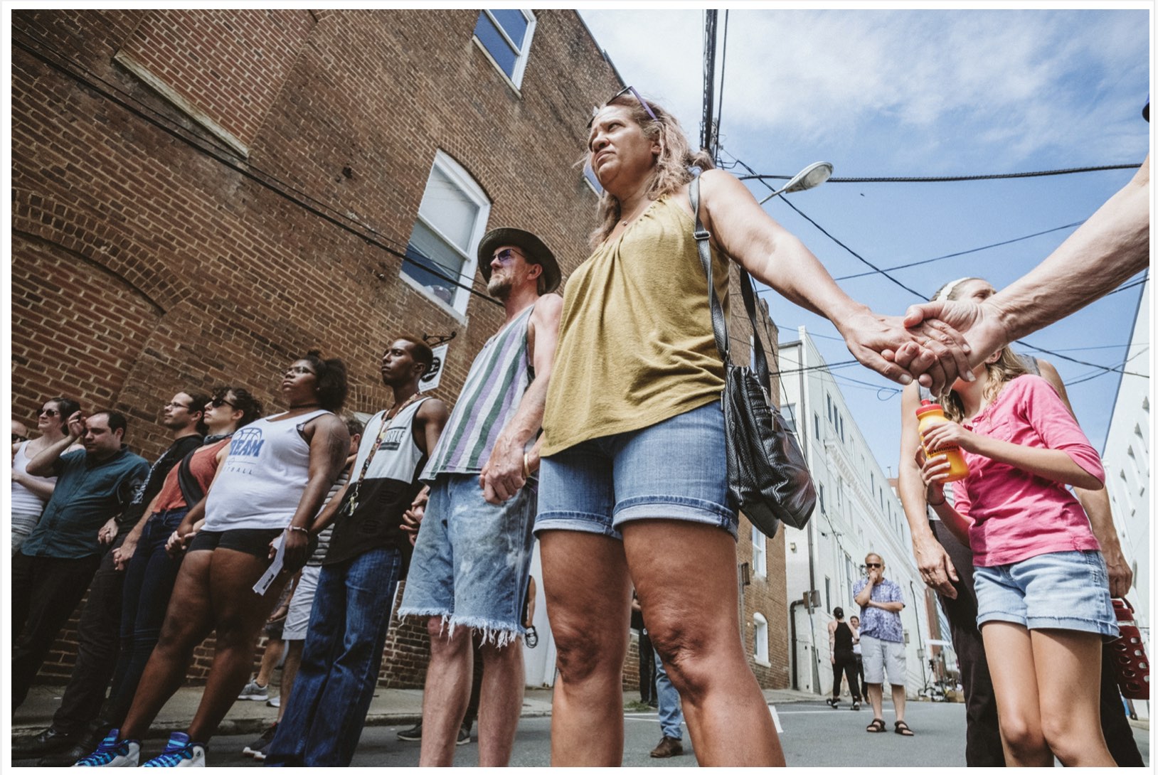 A multiracial crowd holds hands in 4th Street, where Heather Heyer was killed in the 8/12/17 "A12" car attack