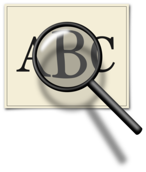 Magnifying glass with handle enlarging the letters ABC on a piece of paper.