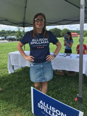 Albemarle County Board of Education candidate Allison Spillman wearing her campaign t-shirt at her booth under a tent