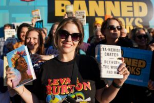20231018 MoveOn Bookmobile Crowd group shot holding books, woman in center wearing MoveOn/Levar Burton t-shirt