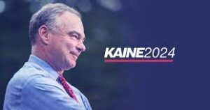 Side profile photo of Senator Tim Kaine wearing a blue shirt and red tie with the words "Kaine2024" written to his right