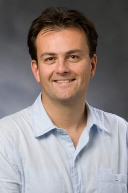 Official UVA photo of Professor Laurent Dubois wearing a light blue shirt and smiling
