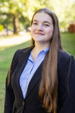 Summer intern Frances Summers smiles from her place on a lawn at UVA.