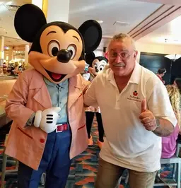 Photo of Bo Sacks standing next to someone wearing a lifesized Mickey Mouse head.